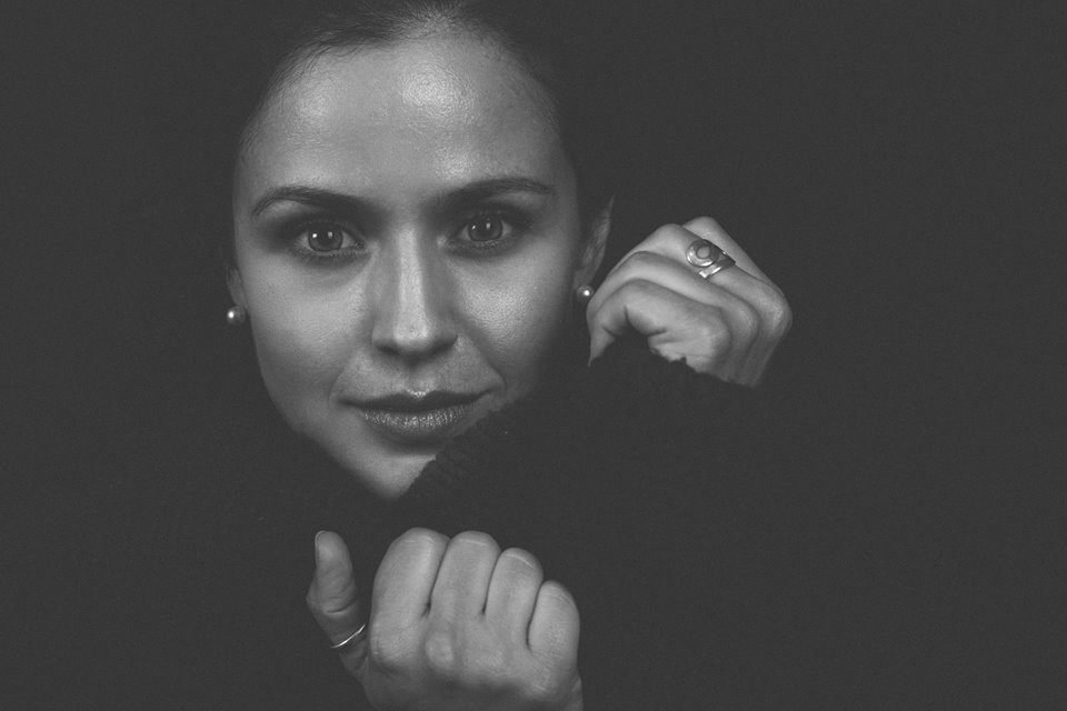 Low light black and white portrait of a woman with her hands raised to her face