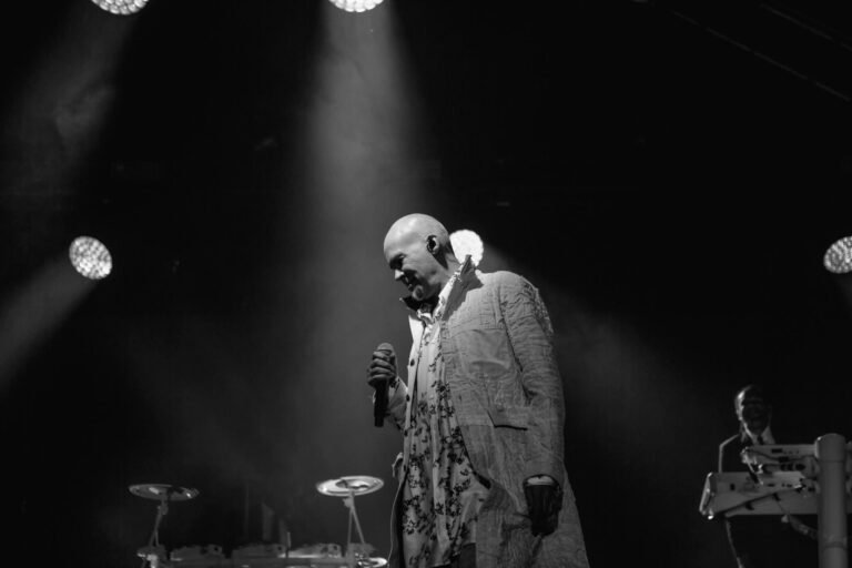 Black and white photograph of The Human League vocalist in a patterned suit under festival spotlights