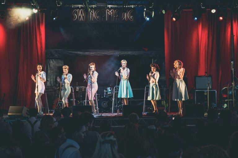 A six-piece vintage girl group singing on the Swingamajig stage in Birmingham between red curtains