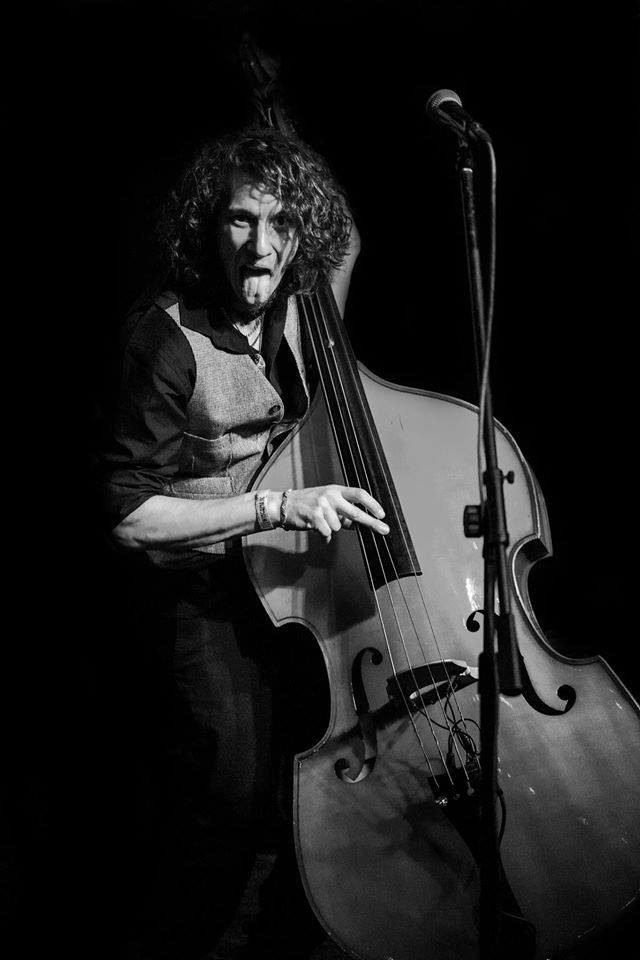 Black and white photograph of a curly-haired double bass player performing live