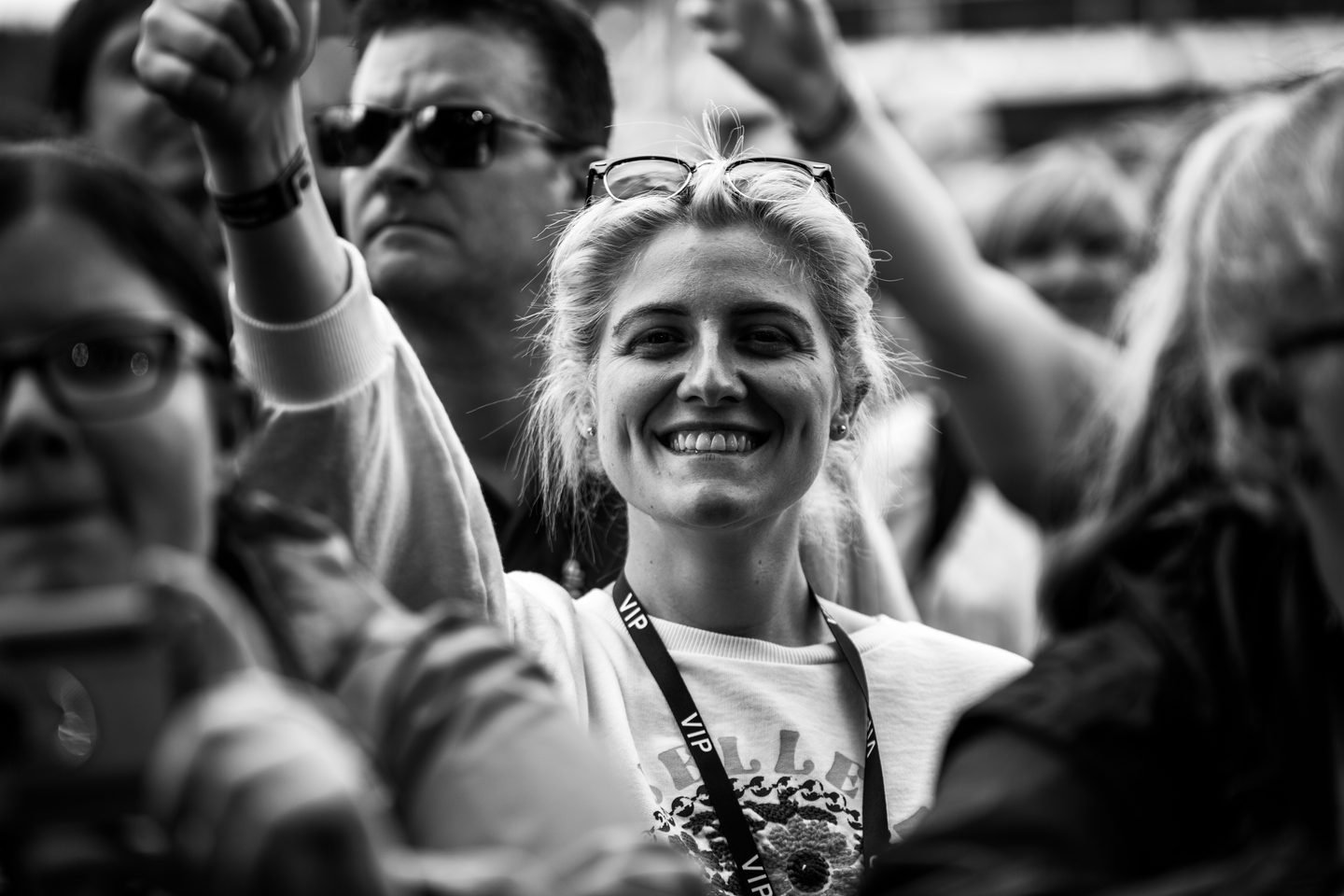Black and white photograph of a woman with a VIP lanyard beaming in the crowd at Solihull Summerfest