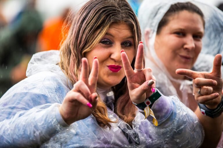 Two women in rain ponchos making peace signs at Solihull Summerfest