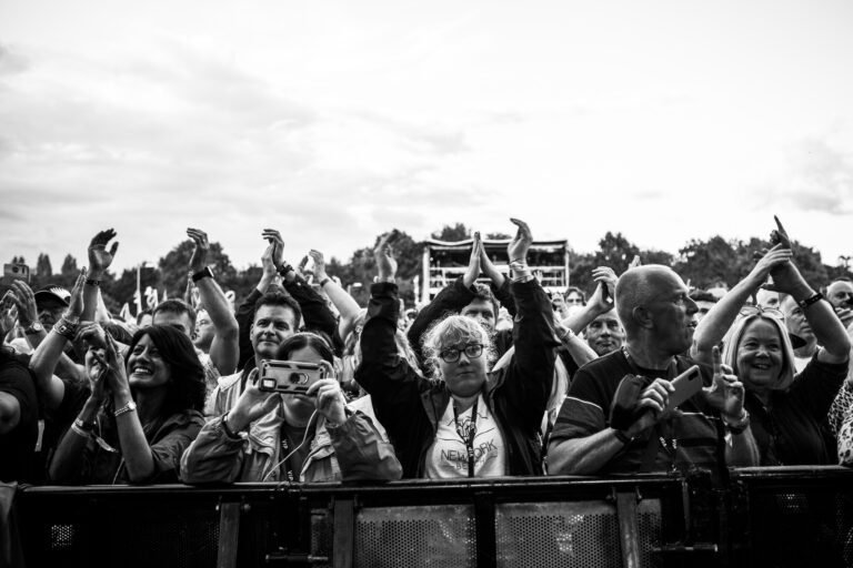 Black and white wide photograph of a festival crowd clapping at the barrier at Solihull Summerfest