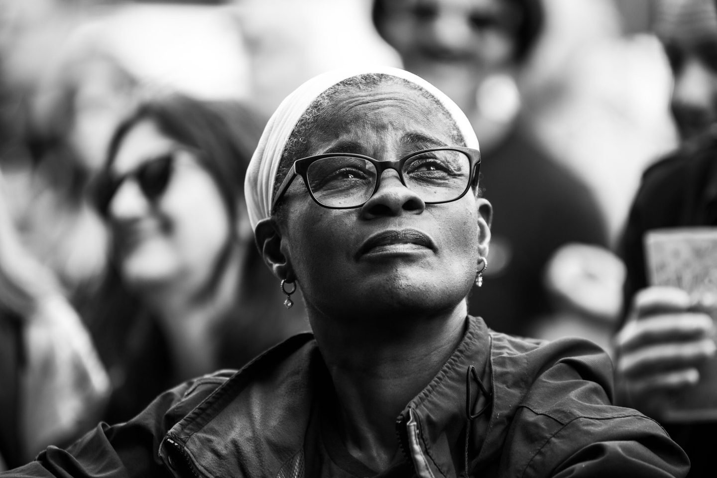 Black and white portrait of a woman in glasses looking up towards the stage at Solihull Summerfest