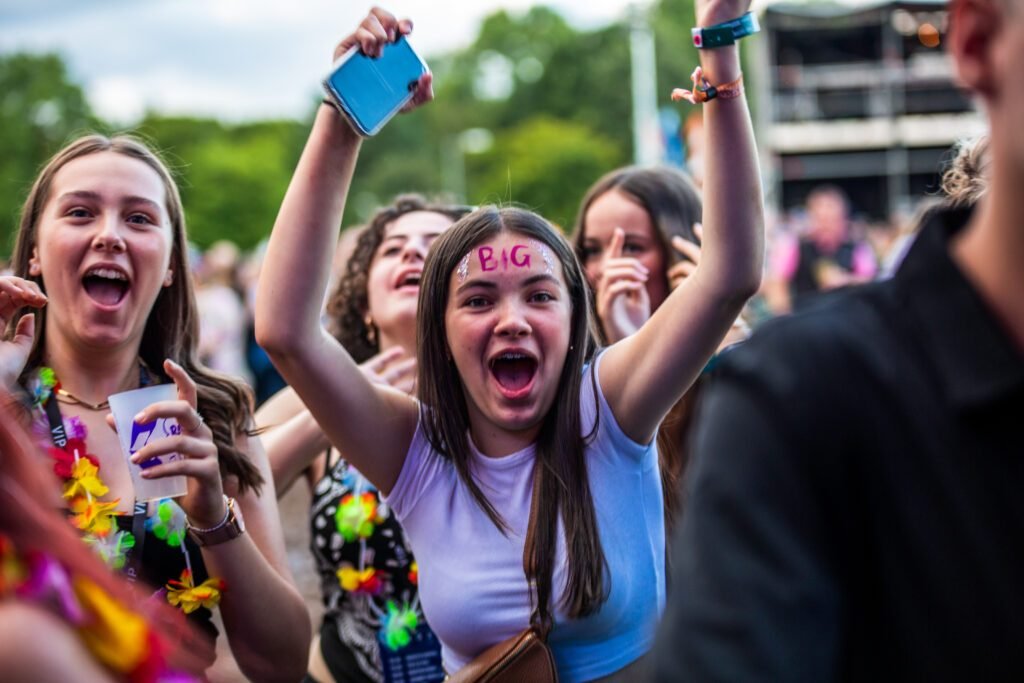 Excited teenagers cheering with arms in the air at Solihull Summerfest