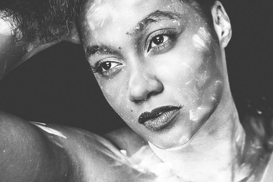 Black and white close-up beauty portrait of a woman with white body paint across her face