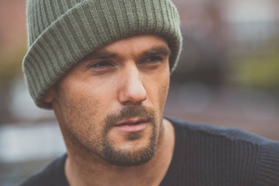 Outdoor portrait of a man in a green beanie in soft natural light