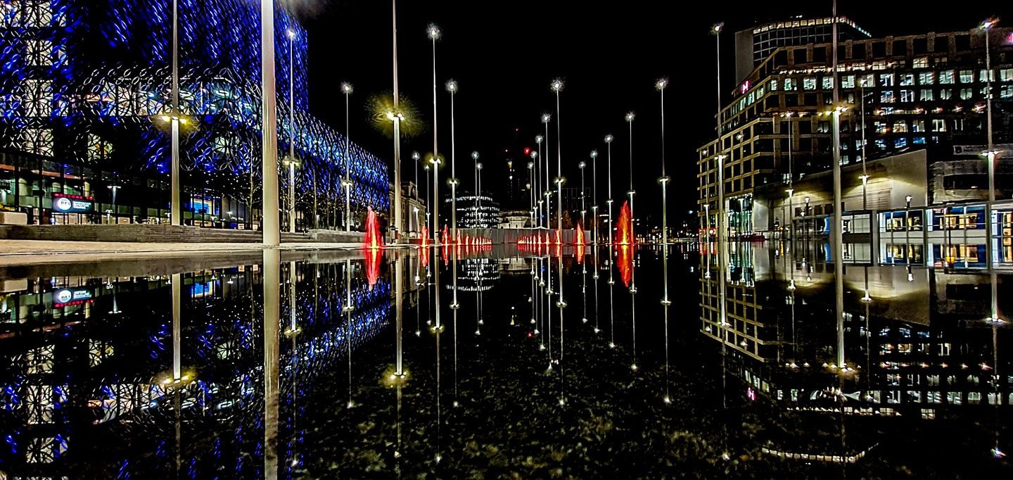 Panoramic night view of Centenary Square in Birmingham, its lights reflected in still water