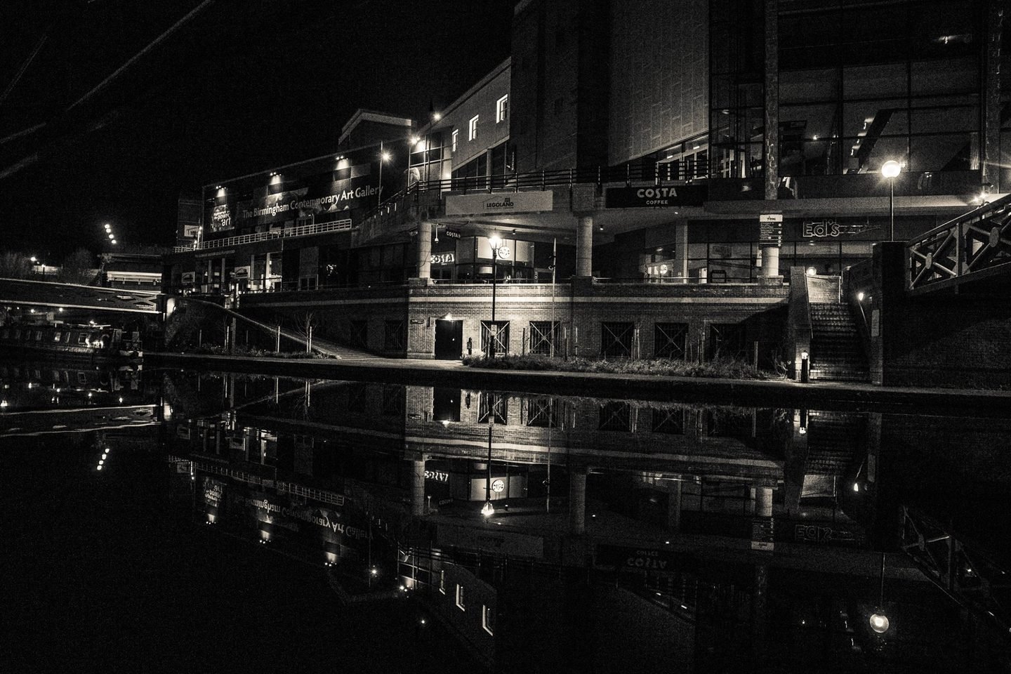 Black and white night photograph of a Birmingham canal side with buildings reflected in the water