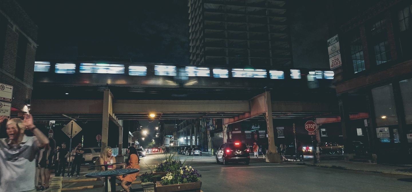 A Chicago L train blurs across an overhead track above a night street