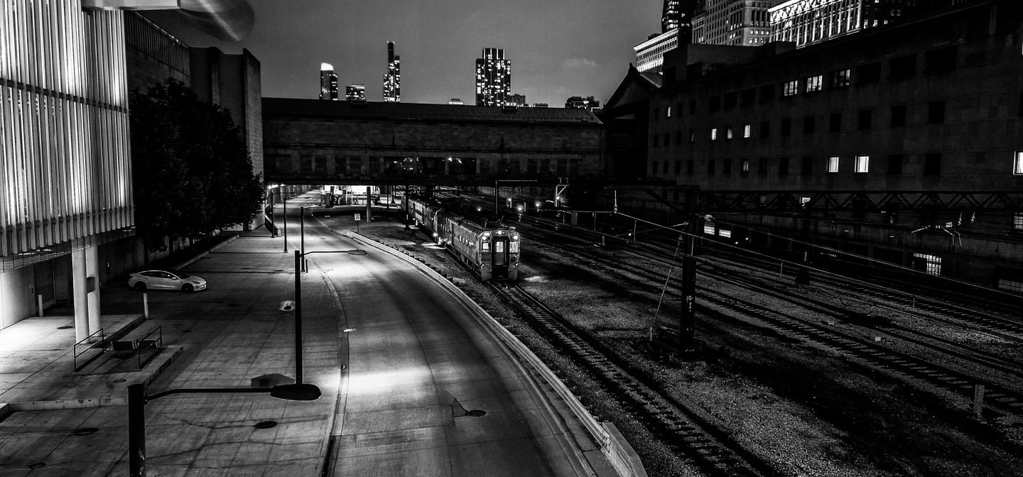 Black and white night photograph of the Chicago Metra train yard and city skyline