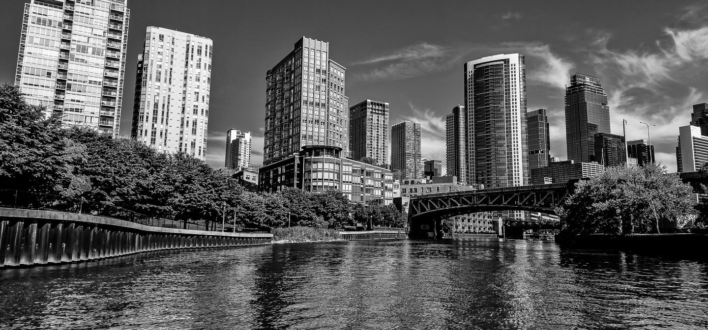 Black and white photograph of the Chicago River with a bridge and high-rise towers