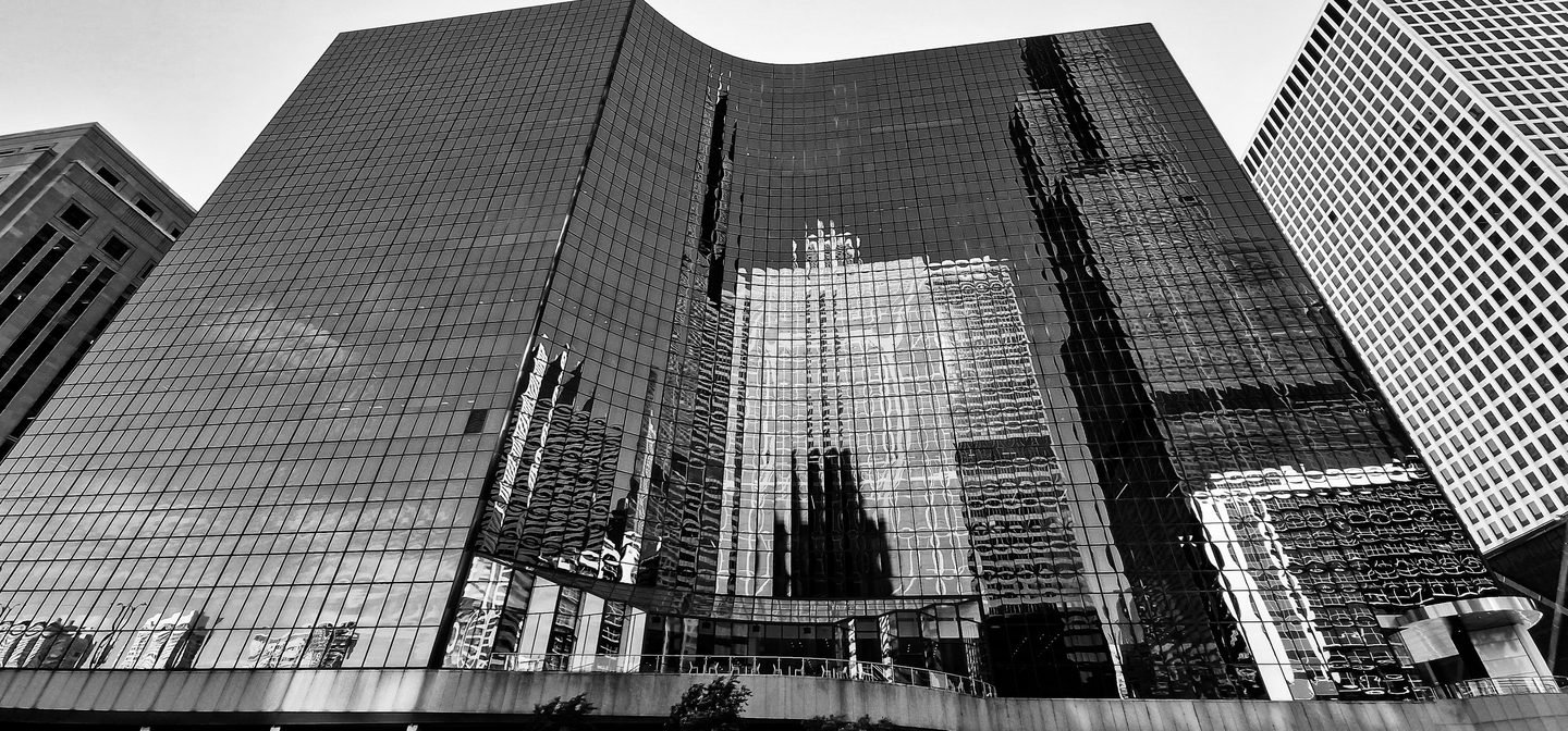 Black and white photograph of reflections across a curved glass building in Chicago