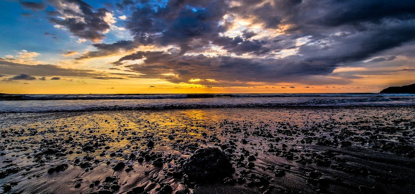 A rocky Costa Rica beach at sunset under dramatic clouds