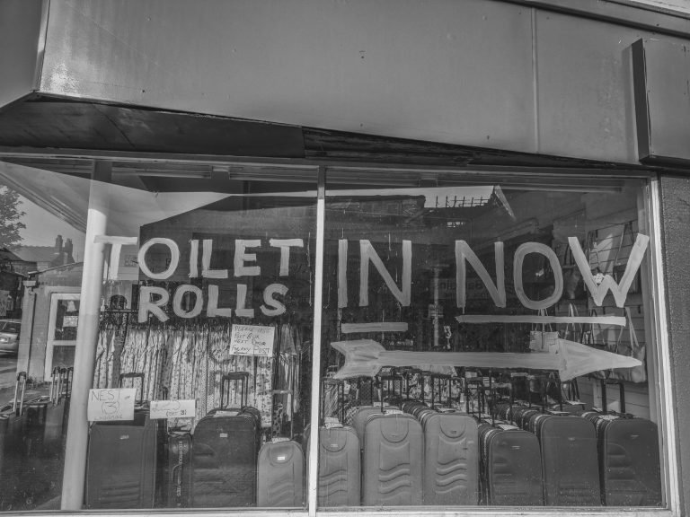 A shop window sign reading Toilet Rolls In Now above rows of suitcases, Birmingham lockdown 2020