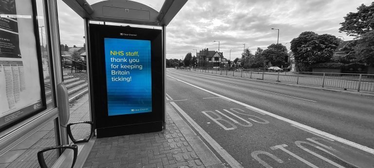 A bus stop screen thanking NHS staff beside an empty road, Birmingham lockdown 2020