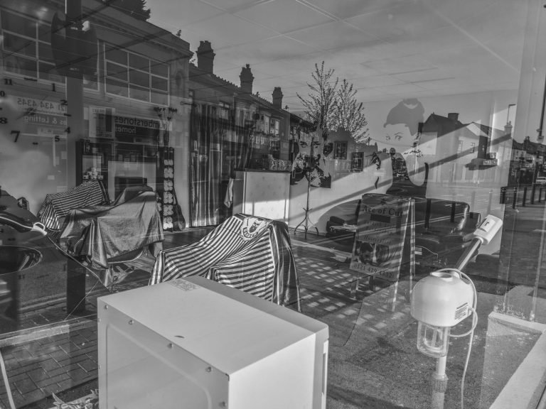 Reflections in the window of a closed barber's shop, Birmingham lockdown 2020