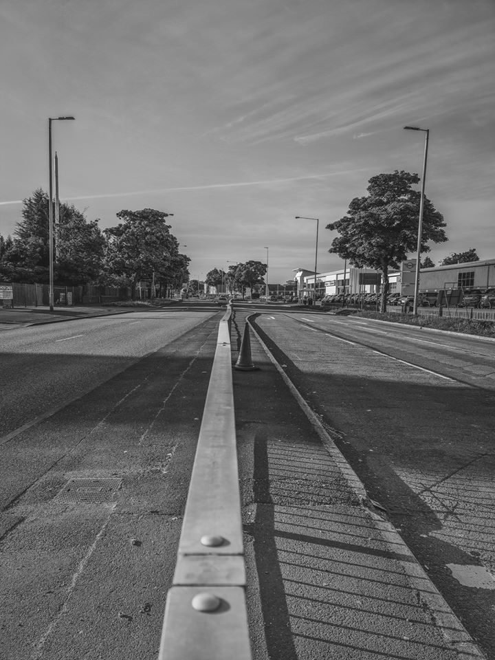 Black and white photograph down the central reservation of an empty dual carriageway, Birmingham lockdown 2020