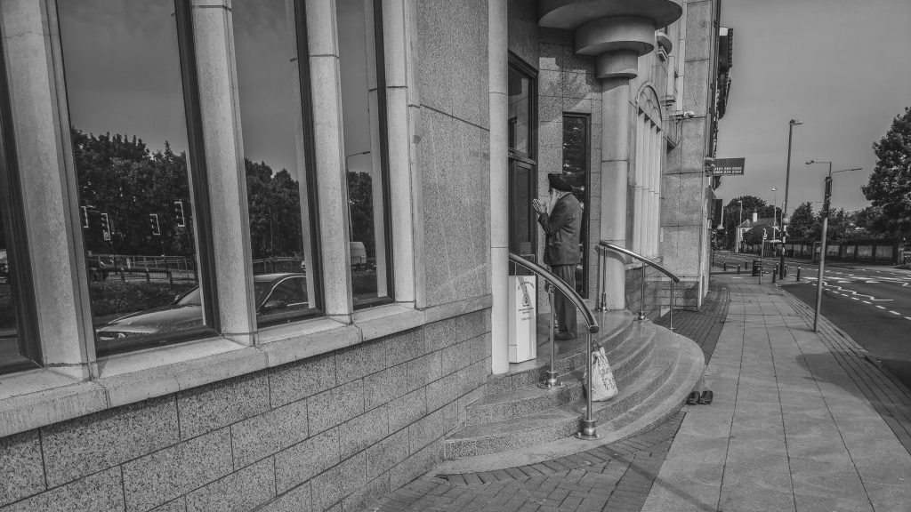 Black and white photograph of a lone figure on the steps of a stone building, Birmingham lockdown 2020