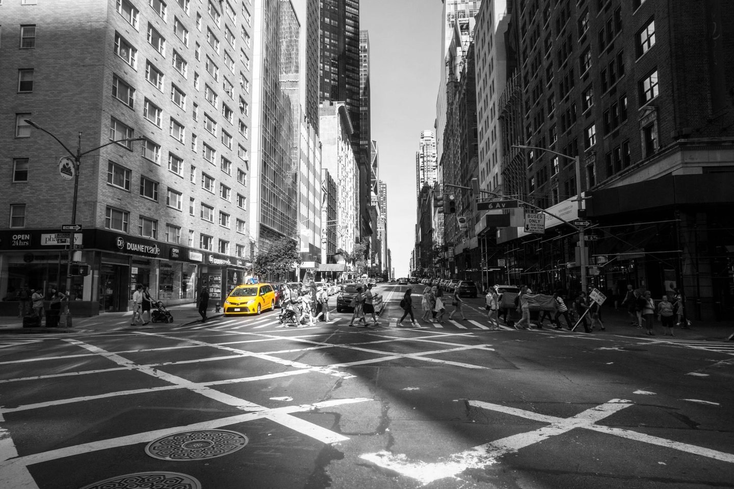 Black and white street scene on Sixth Avenue in New York with a single yellow taxi in colour