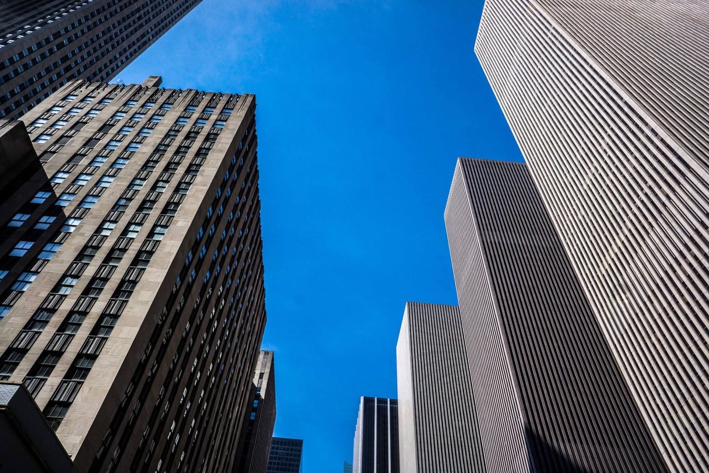 Looking up at Rockefeller Center skyscrapers against a deep blue sky