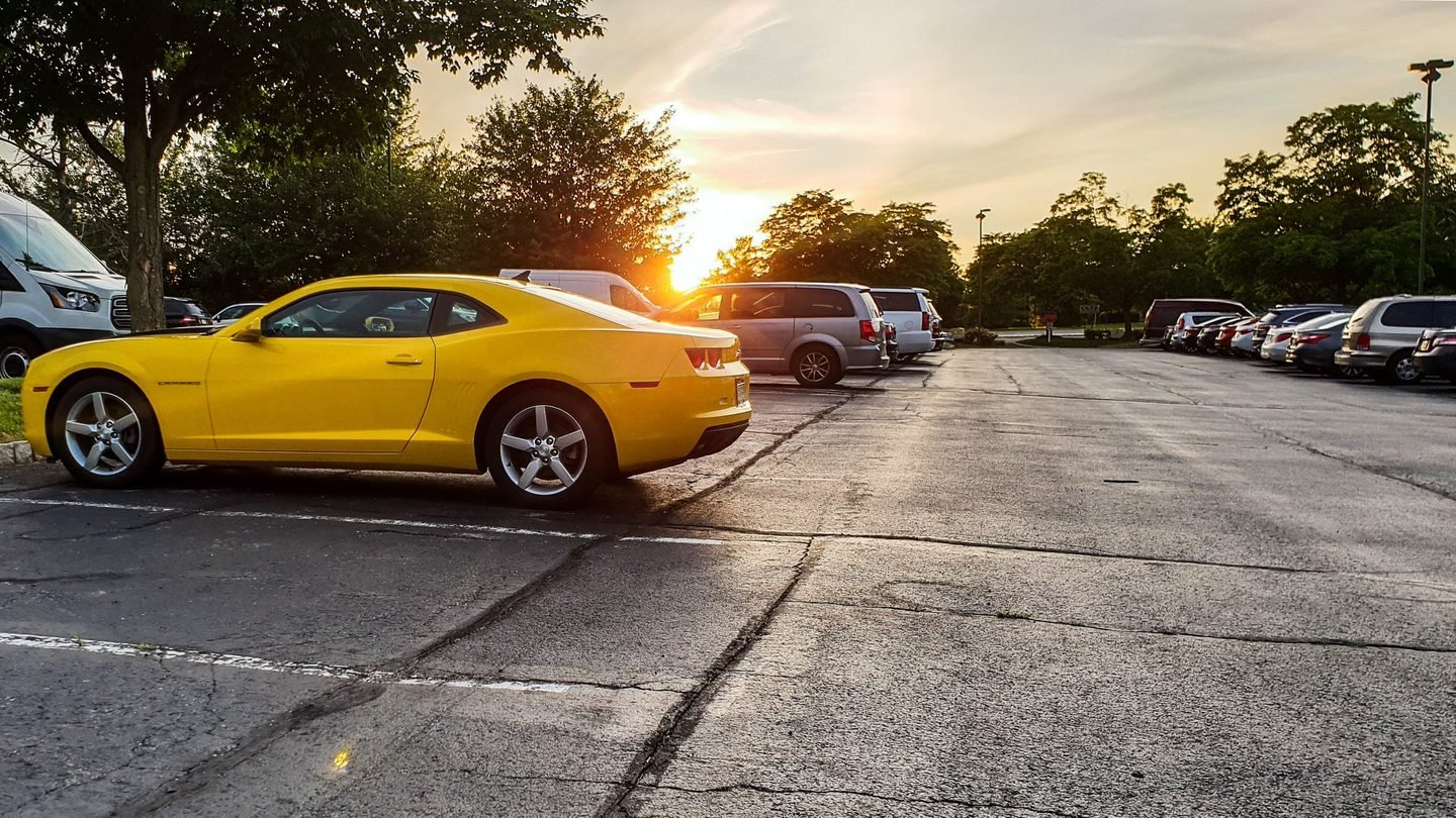 A yellow Chevrolet Camaro in a car park at sunset in New York