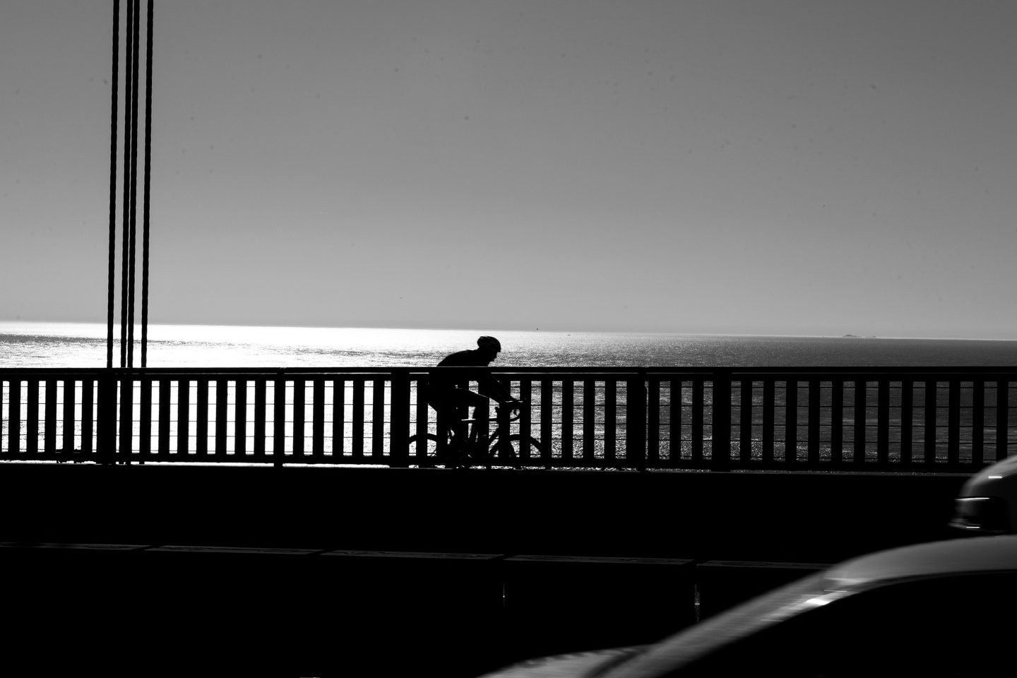 Black and white silhouette of a cyclist crossing the Golden Gate Bridge