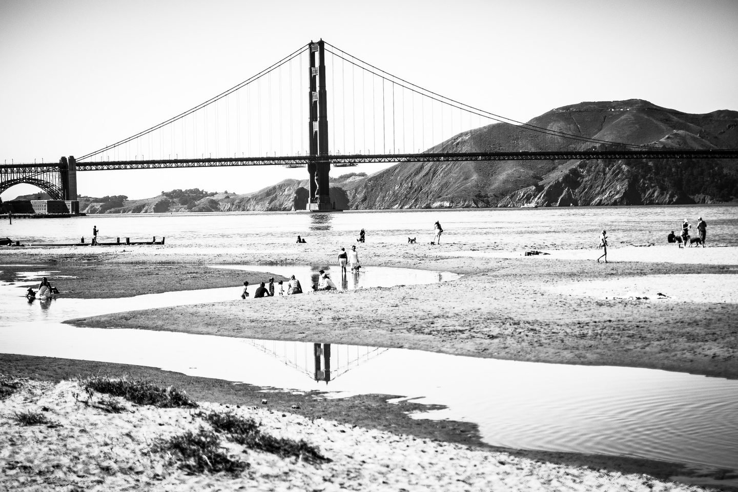 Black and white photograph of the Golden Gate Bridge reflected in water at Crissy Field beach