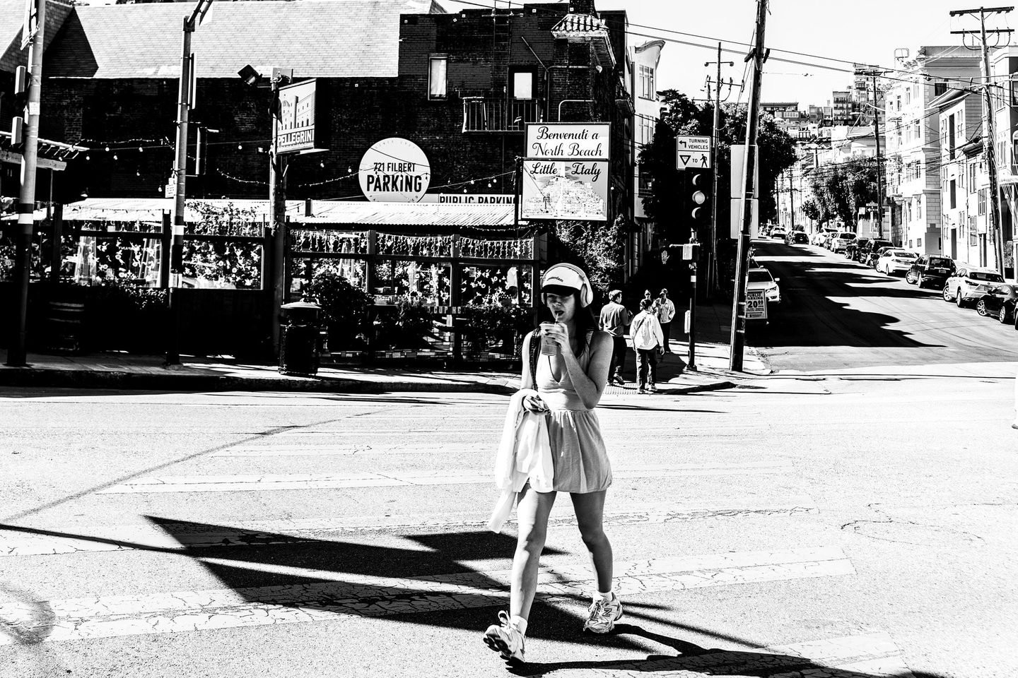 Black and white photograph of a woman crossing a North Beach street in San Francisco